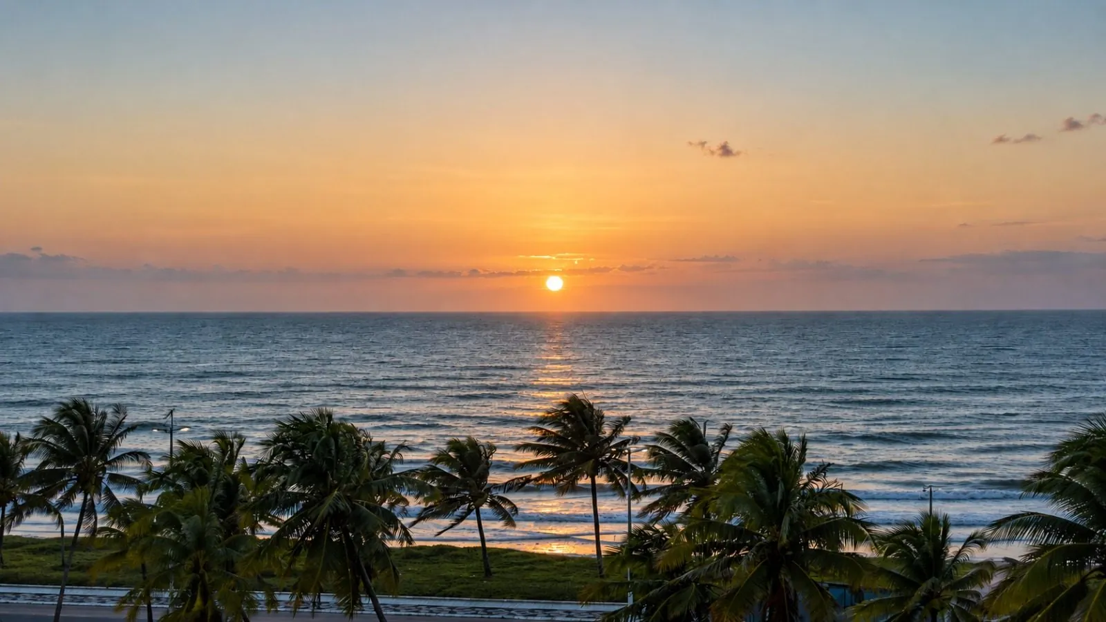 Pôr do sol sobre o mar da Riviera, com coqueiros em primeiro plano